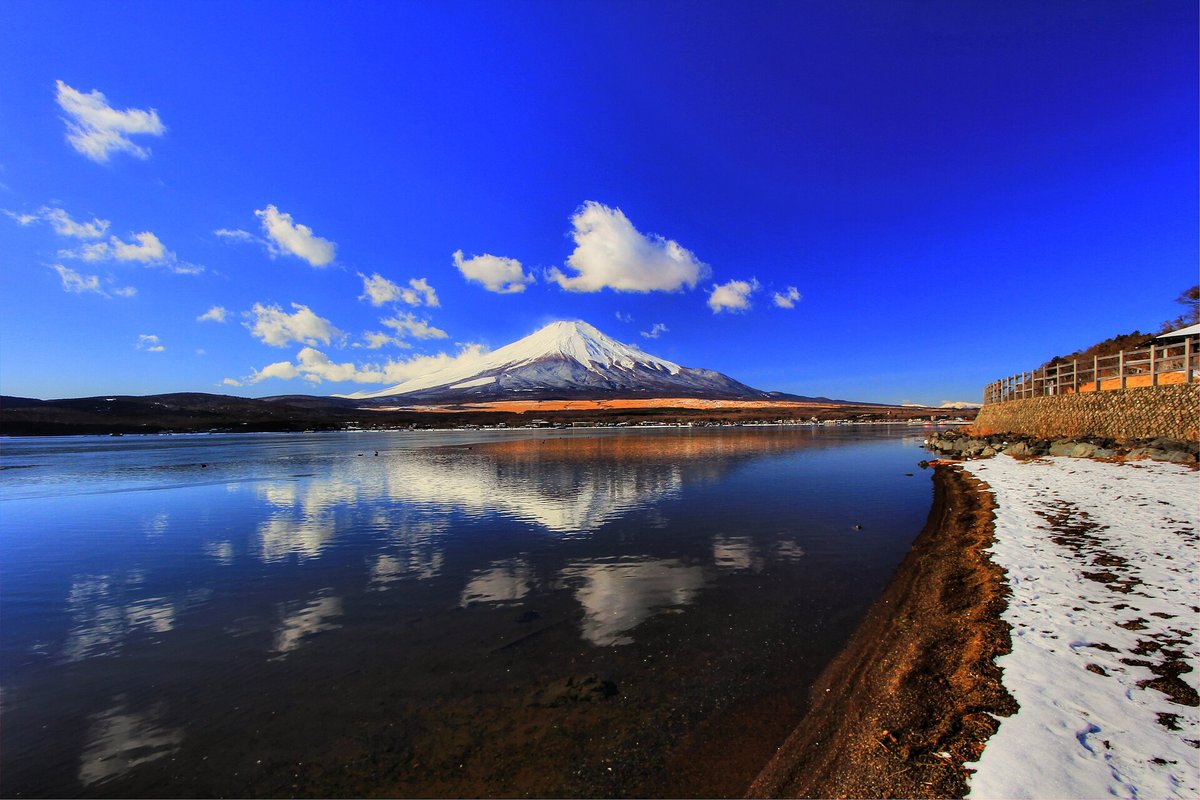 1 月長池親水公園一帶的湖岸:無風的湖面清楚倒映雪頂富士山和白雲,右邊岸上有殘雪,石砌護岸上架著木柵