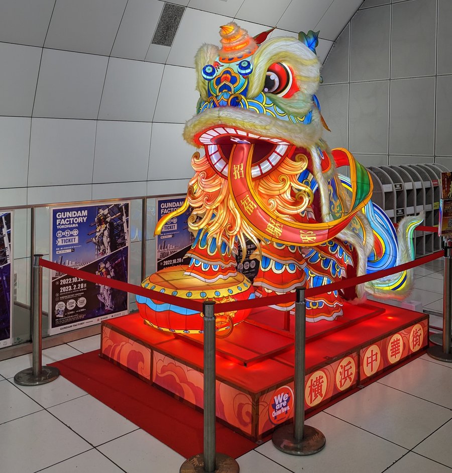 元町・中華街站站內展示的大型舞獅燈飾,獅口咬著寫有「招福」字樣的紅布條,台座上印著「横浜中華街」,周圍拉著紅色圍欄